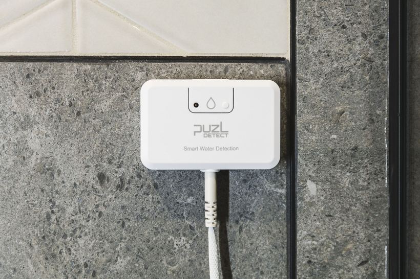 PuzL Detect mounted on a stone wall beside the shower