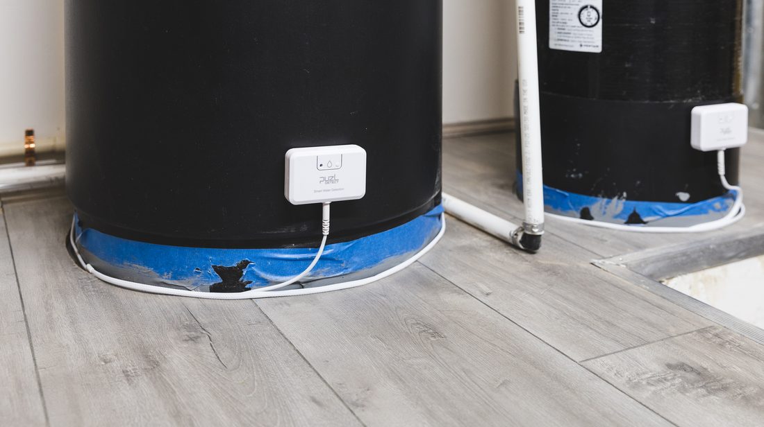 Two water tanks, each with a PuzL Detect mounted low and the sensing cable wrapped around its base