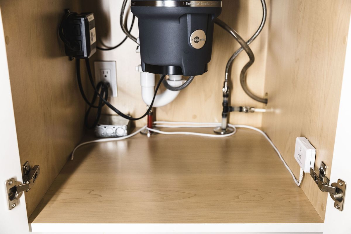 PuzL sensing cable routed around the plumbing inside a sink cabinet